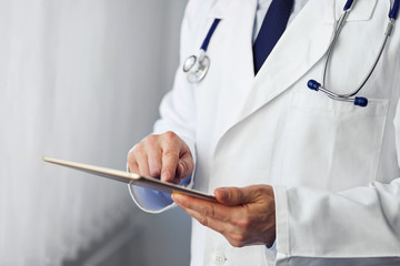 Male doctor presses on screen digital tablet