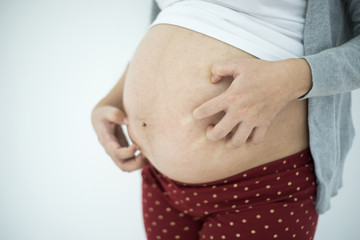 Pregnant woman scratching belly