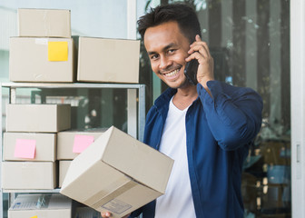 Concept modern new asian entrepreneur. E-commerce business owner calling to supplier to confirm order and reviewing checklist of customer address before sent box of product by parcel post.