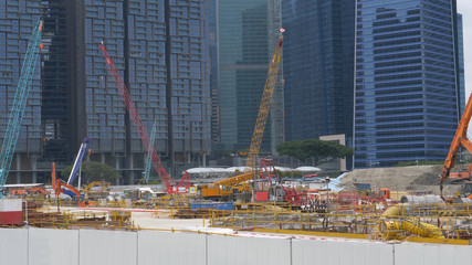 Bustling construction site full of people and machinery near business offices