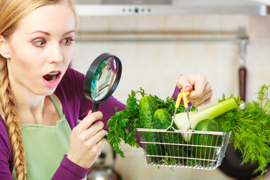 Woman looking through magnifier at vegetables basket