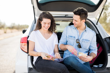 Couple eating sandwiches in car boot