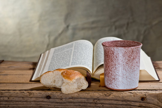 Bible, Chalice And Bread on the Wooden Desk.