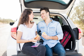 Romantic couple on road trip having sandwiches