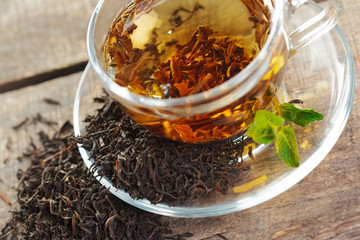 cup of black tea with mint leaves on a wooden table