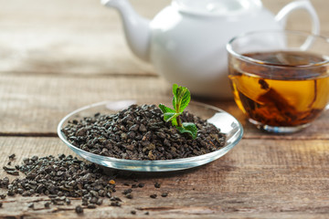 cup of black tea with mint leaves on a wooden table
