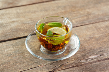 cup of black tea with mint leaves on a wooden table