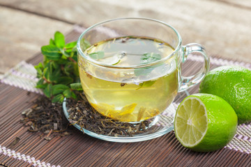 cup of black tea with mint leaves on a wooden table