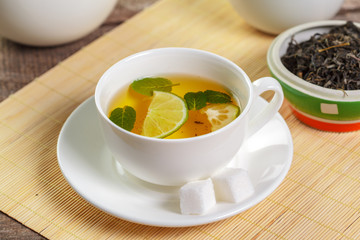 cup of black tea with mint leaves on a wooden table