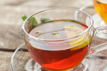 cup of black tea with mint leaves on a wooden table