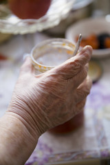 Grandmother takes a glass jar with spoon from the table. Hand close up