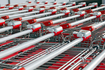 A lot of shopping carts with locks standing inserted one into the other.