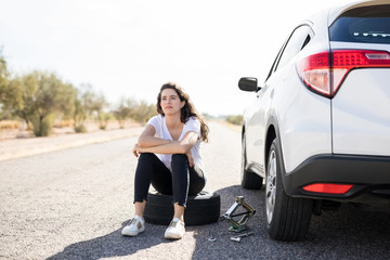 Woman looking upset with flat tyre on her car