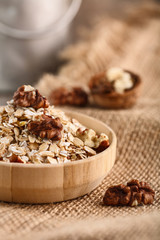 Dry rolled oatmeal in wooden bowl on textile background.