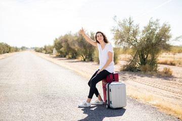 Female tourist hitchhiking along a road