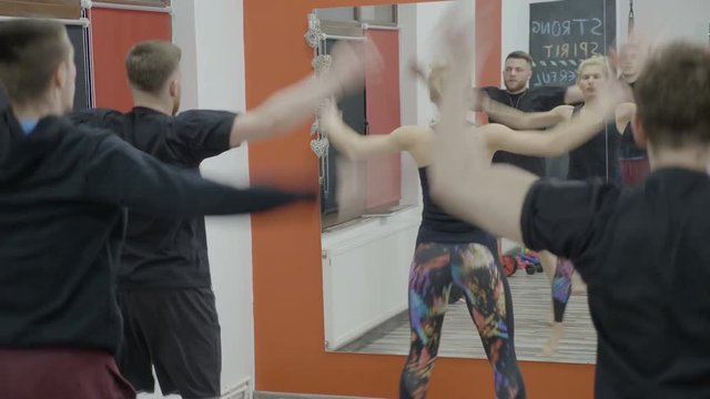 Group of male coworkers jumping and doing aerobic class together with their female manager at the gym as part of the team building program