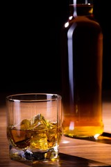 Glass of Whiskey and Bottle on Background