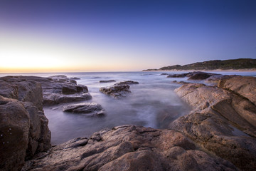 Fototapeta na wymiar Long exposure of waves rushing over the rocks just after sunset at Surfers Point near Margaret River in Western Australia.