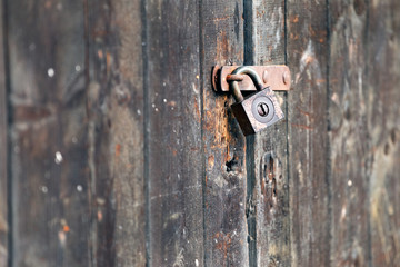 Old rusty padlock on wooden gate