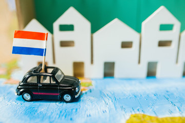toy car carries the flag of the Netherlands against the white houses