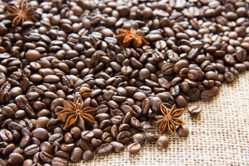 Roasted coffee beans are scattered on sackcloth with anise