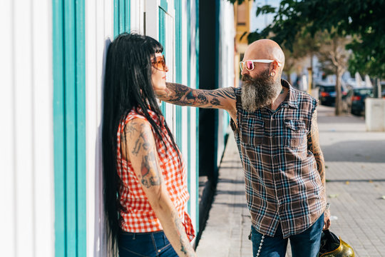 Mature hipster couple face to face on sidewalk