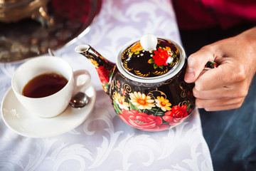 left hand holds a teapot