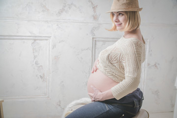 pregnant woman at home stands at the wall