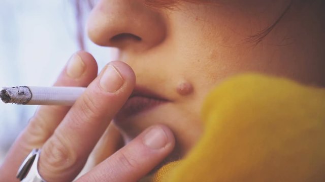 close up on mouth of a woman smoking a cigarette