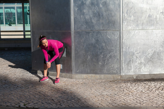 Young woman squatting against wall