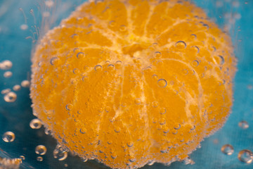 orange under the water purified, bubbles on it, blue background