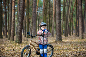 Young boy with bicycle with drinking clear water