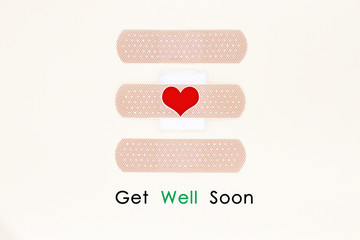 Cute get well soon card. Handmade Greeting Card Making Ideas with sticky plaster and sticker heart on yellow cream background .Top view and flat lay.
