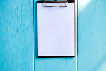 Clipboard with white sheet on wood background. Top view.Vintage style.