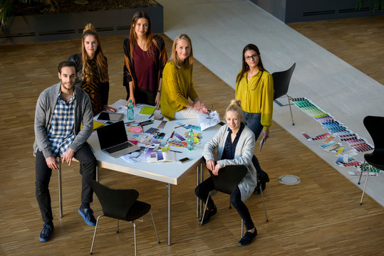 Team of male and female designers by design studio table, high angle portrait