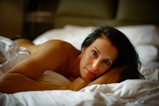 Nude woman lying on bed looking at camera