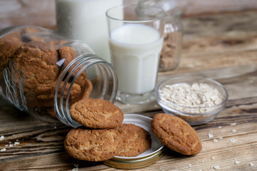 Oat homemade cookies and milk in a glass and a bottle on a wooden table