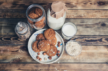 Oat homemade cookies and milk in a glass and a bottle on a wooden table. Top view