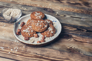 Pile of homemade oatmeal cookies on white ceramic plate on blue napkin and glass of milk, isolated on white background
