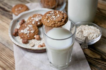 Oat homemade cookies and milk in a glass and a bottle on a wooden table