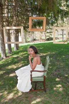 Portrait of bride wearing wedding dress, sitting in chair, outdoors