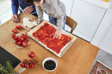 Grandmother and grandson making pizza in kitchen, elevated view