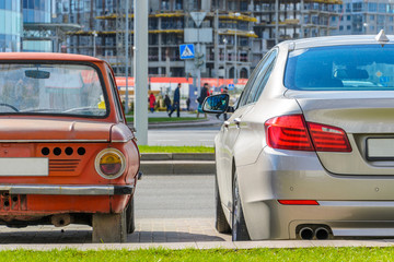 Rear view of two cars of different eras standing side by side in the city. The concept of...