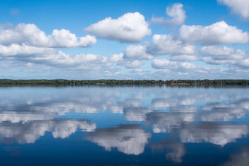 Wolken am blauen Himmel mit Spiegelbild im Wasser