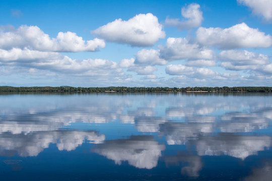 Wolken am blauen Himmel mit Spiegelbild im Wasser
