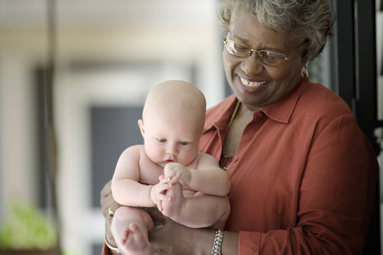 Baby being held by a mature adult woman.