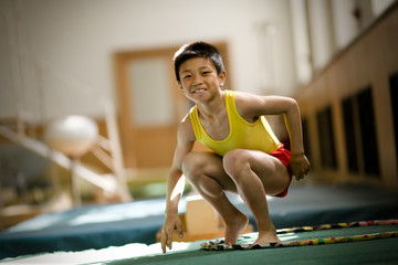 Portrait of a boy playing with a hula hoop in a gym.