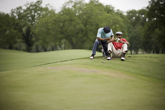 Men sitting on golf course with score card