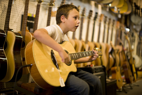 Boy playing guitar in music store