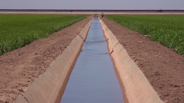 A farmer walks along the US Mexico border with the wall in the background.
